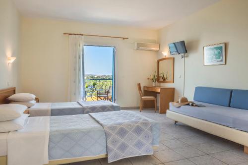 a hotel room with two beds and a couch at Afrato Village Sea View apartments in Trapezaki