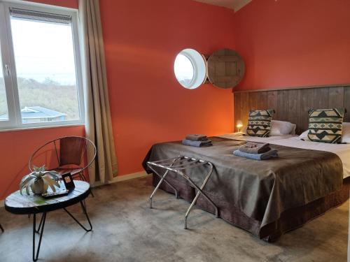 a bedroom with red walls and a bed and a chair at Beach Hotel Oostvoorne in Oostvoorne