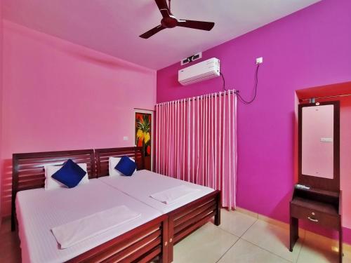 een slaapkamer met paarse muren en een bed met een ventilator bij Oshin Home Stay in Cochin