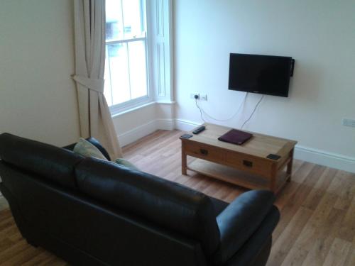 Sala de estar con sofá negro y mesa de centro en The Bradworthy Inn, en Holsworthy