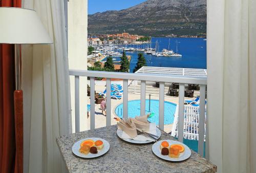 a balcony with a table with plates of fruit on it at Marko Polo Hotel by Aminess in Korčula