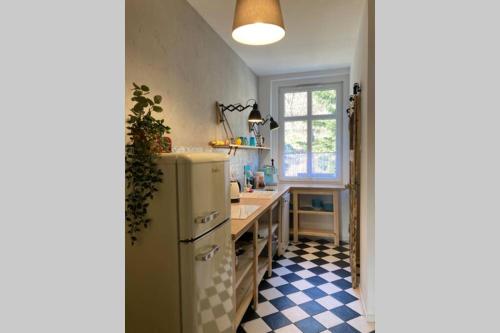 a kitchen with a refrigerator and a checkered floor at Apartament Stara Kamienica 1930r. in Kłodzko