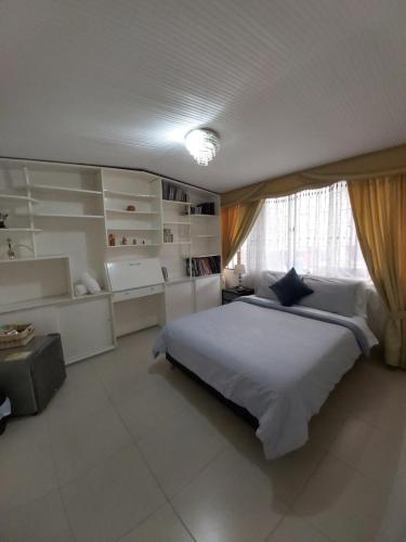 Un dormitorio con una gran cama blanca y una ventana en Casa Coffice, en Bogotá