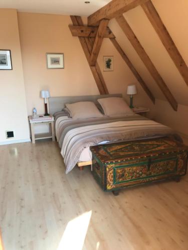 um quarto com uma cama grande e piso em madeira em La maison rouge em Ostheim