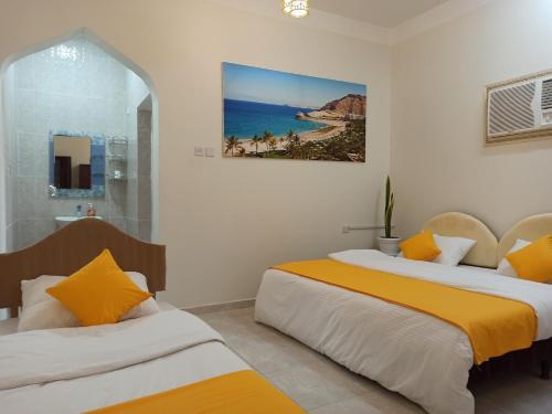 um quarto com duas camas e um quadro na parede em Nima guest house em Nizwa