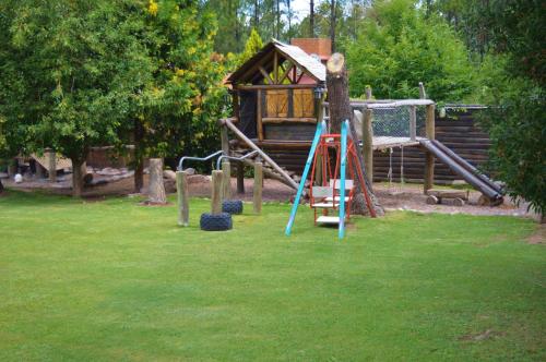 a playground in a park with a log cabin at Cabaña Suiza in Cacheuta