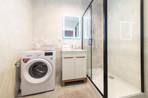uma casa de banho com uma máquina de lavar roupa e um lavatório em Apartamenty Jurowiecka em Bialystok