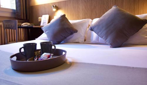 a hotel room with a bed with pillows and a tray of drinks at Le Strasbourg Hotel in Montpellier