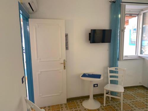 a room with a door and a chair and a television at Appartamenti Tina in Villa Restituta in Ischia