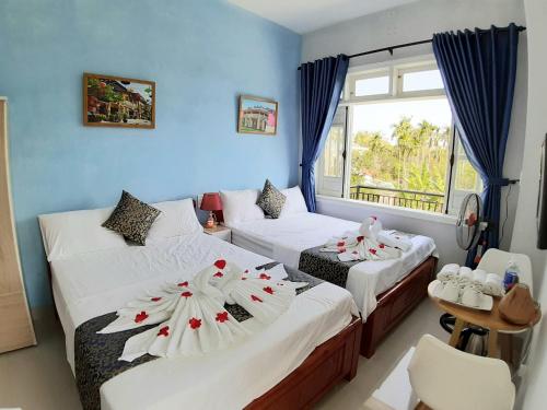 um quarto com duas camas com flores em Ngoc Diep Homestay Hoi An em Hoi An
