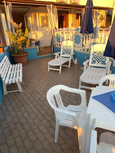 a patio with white chairs and tables and umbrellas at Appartamenti Tina in Villa Restituta in Ischia
