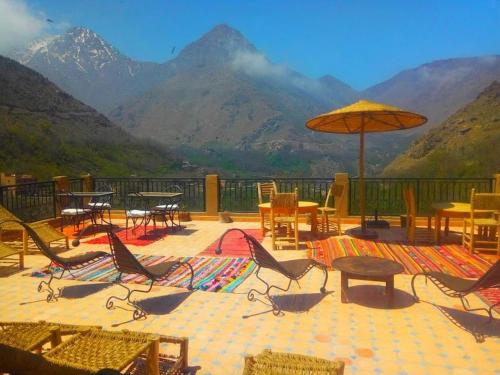 a patio with chairs and tables and an umbrella at Afla Views Imlil in Imlil
