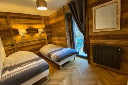 een slaapkamer met 2 bedden in een kamer met houten wanden bij Gîte avec jacuzzi privatif in Crots