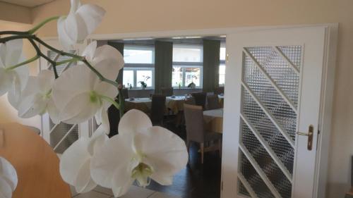 a vase with white flowers in front of a dining room at Lindner's Hotel in Bellheim