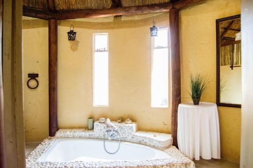 a bath tub in a room with two windows at Shangrila-innibos Country Lodge in Hartbeespoort
