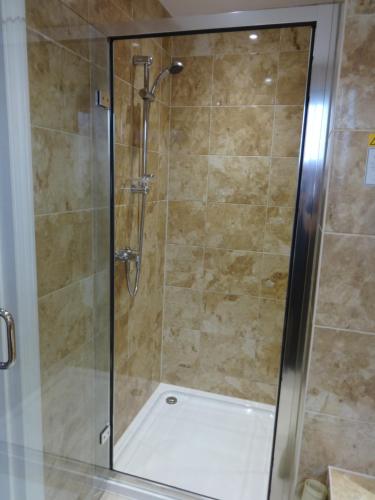 a shower with a glass door in a bathroom at Autumn House in Cambridge