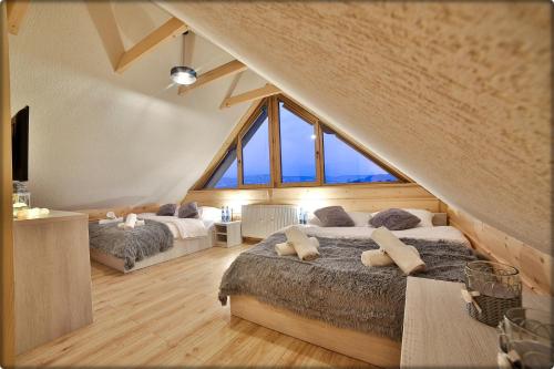 a attic bedroom with two beds and a large window at Zdrojowy Gościniec - domki Rabka-Zdrój in Rabka