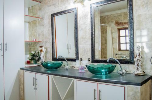 a bathroom with two sinks and a mirror at Shangrila-innibos Country Lodge in Hartbeespoort