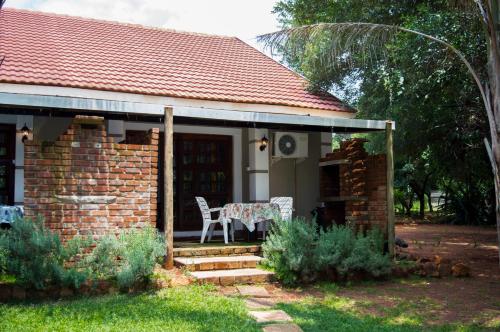 a brick house with a table and chairs on the porch at Shangrila-innibos Country Lodge in Hartbeespoort