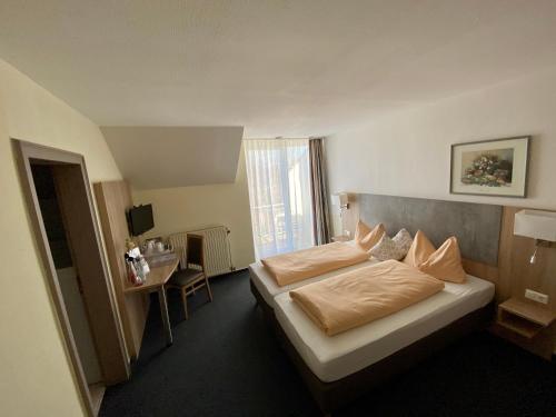 a hotel room with two beds and a desk at Hotel am Rosenbad in Fulda