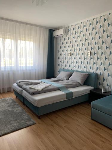 a bedroom with a large bed with a wall at Thermal Next I Weninger Apartman Kiskunhalas in Kiskunhalas