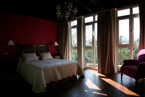 a bedroom with red walls and a bed and windows at Las Casas Rurales Huerta San Benito in Villamayor