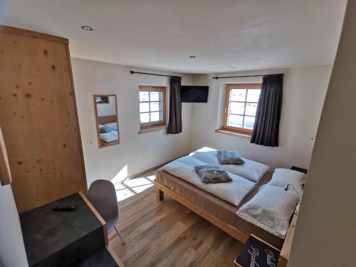 a bedroom with a bed and two windows at Chalet Pizabela Bait da Pizabela in Livigno
