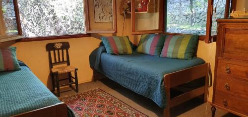 a small bedroom with a bed and a chair at Casa de Montaña inmersa en Bosque Nativo in San José de Maipo