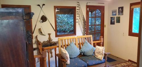 a living room with a couch and two windows at Casa de Montaña inmersa en Bosque Nativo in San José de Maipo