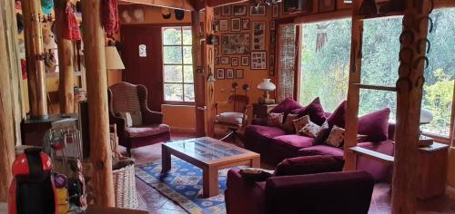 a living room with purple couches and a table at Casa de Montaña inmersa en Bosque Nativo in San José de Maipo
