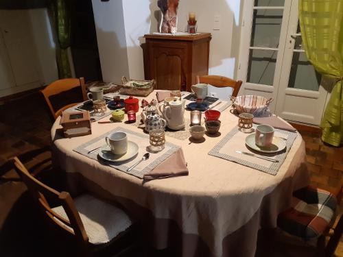 ein Tisch mit einer weißen Tischdecke und Tassen und Untertassen in der Unterkunft La Treille in Treigny