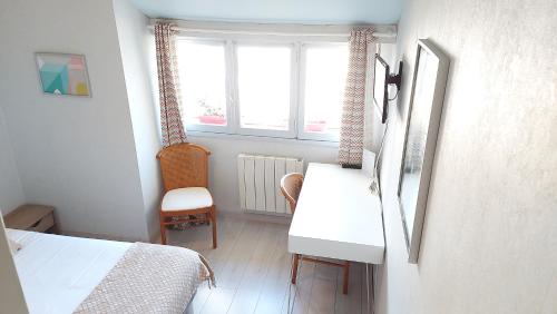a bedroom with a desk and a bed and a window at Logis Hôtel Vannes Nord Le Clos Des Hortensias in Locqueltas