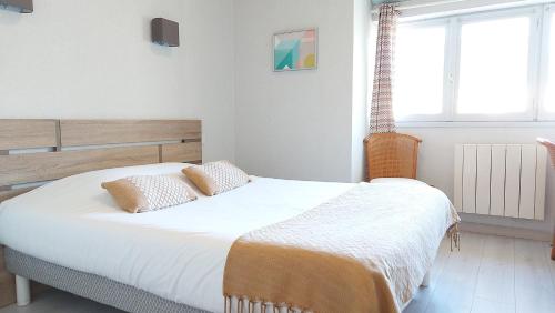 a bedroom with a large white bed with two pillows at Logis Hôtel Vannes Nord Le Clos Des Hortensias in Locqueltas