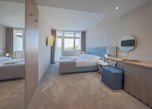 a hotel room with a bed and a desk with a desk at Aminess Vival Port9 Resort in Korčula