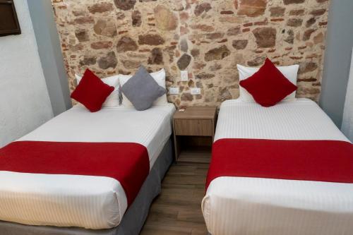 two beds with red and white sheets in a room at Hotel Hidalgo in Querétaro