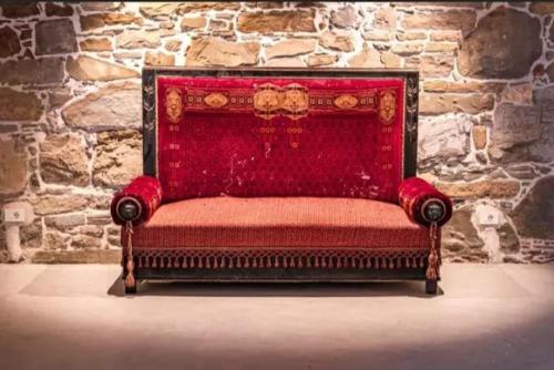 a red couch in front of a stone wall at Dvor Vipolže in Dobrovo