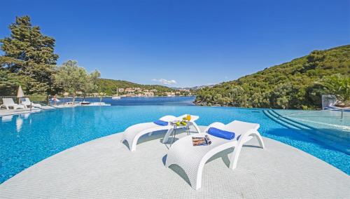 a pool with white chairs and a swimming pool at Aminess Vival Port9 Resort in Korčula