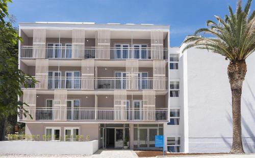 an apartment building with a palm tree in front of it at Aminess Vival Port9 Resort in Korčula