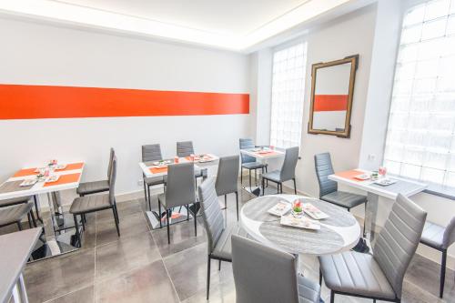 a dining room with tables and chairs and a mirror at Hôtel Ligure in Cannes