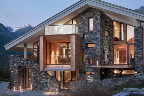 a large stone house with a glass facade at Mineral Lodge & Spa in Villaroger