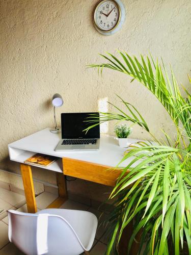 a desk with a laptop on it with a clock on the wall at Departamento Rinconcito olivo, 5min centro, home office in Valle de Bravo