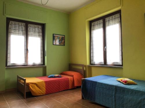 2 Betten in einem Zimmer mit grünen Wänden und Fenstern in der Unterkunft Ca' di Burghi in Busca