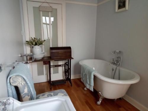 een badkamer met een bad, een wastafel en een spiegel bij The Oystercatcher in Rostrevor