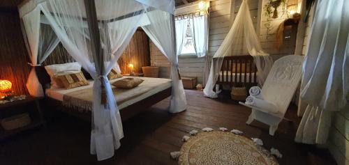 a bedroom with a bed with drapes and a crib at Hotel ECOLODGE LE RAVORAHA in Sainte Marie