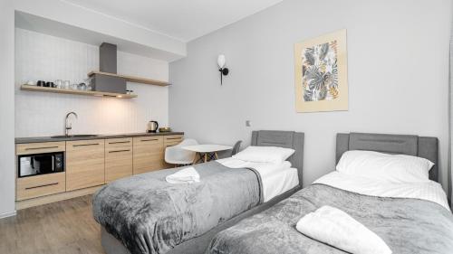 two beds in a room with a sink and a kitchen at Comfy Apartments - Park Technologiczny in Gdynia