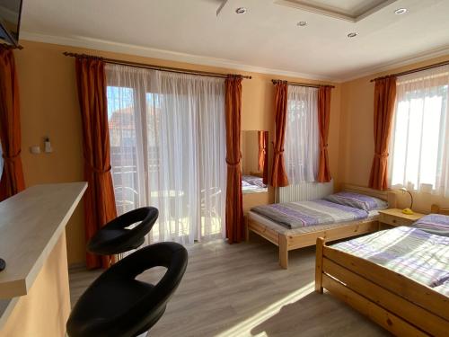 1 Schlafzimmer mit 2 Betten, einem Schreibtisch und Stühlen in der Unterkunft Millennium Lux Apartments in Hajdúszoboszló