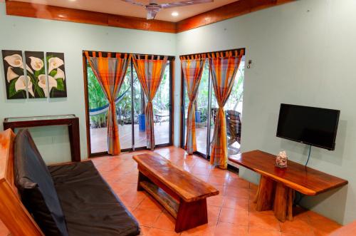 a living room with a tv and a couch and a table at Tico Adventure Lodge in Sámara