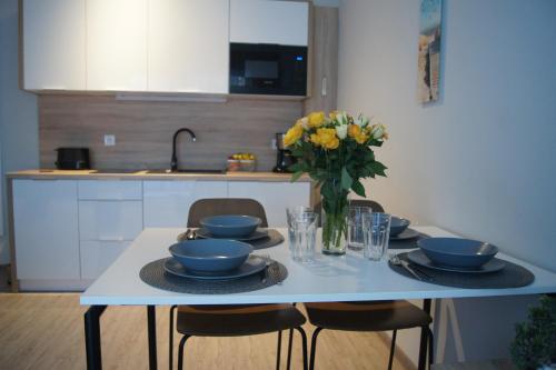 a table with plates and bowls and a vase of flowers at Apartament Elvira, Grunwaldzka 12C in Pobierowo