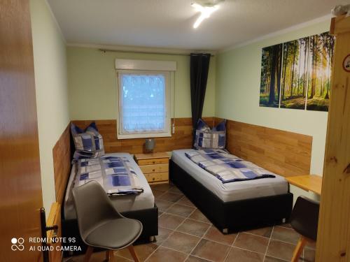 2 Betten in einem Zimmer mit 2 Stühlen und einem Fenster in der Unterkunft Großzügige Ferienwohnung am Waldesrand im Seenland in Laubusch