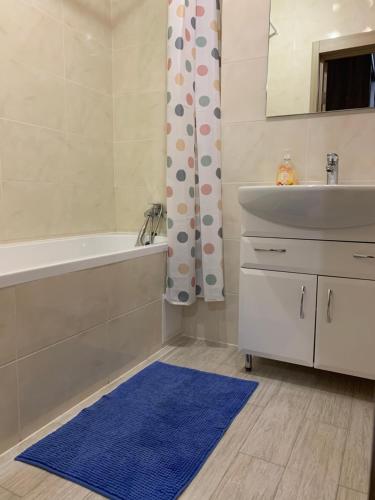 a bathroom with a tub and a sink and a blue rug at 073 Уютная квартира ЖК «Софиевская Слободка» in Vyshneve